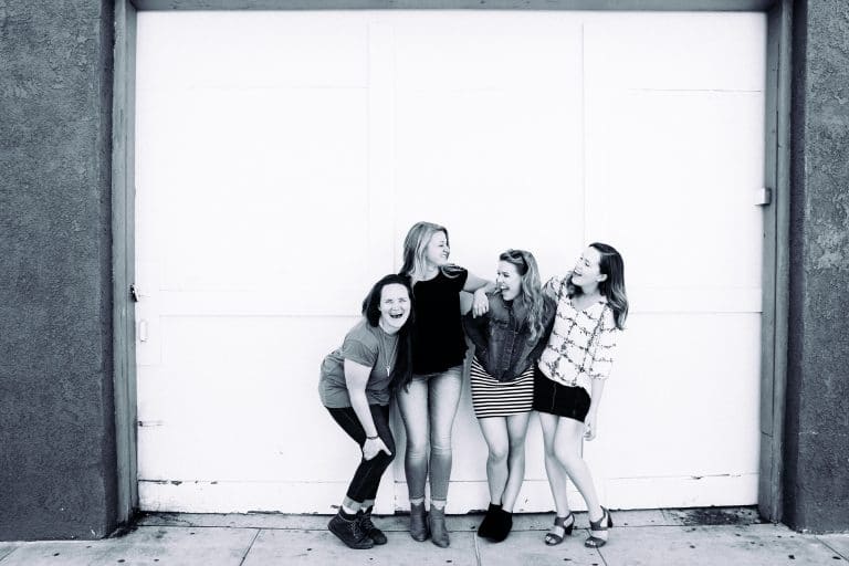 black and white image of four women laughing in front of garage door