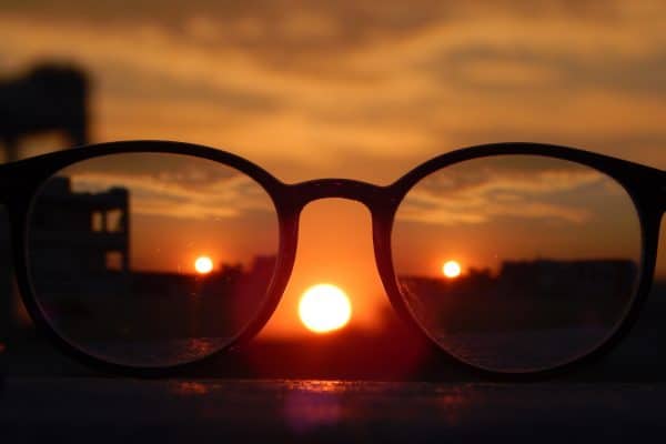 black frame glasses held up to a sunset